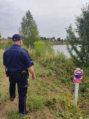 Na zdjęciu policjant kontrolujący zbiornik wodny.