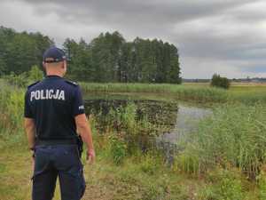 Na zdjęciu policjant kontrolujący zbiornik wodny.