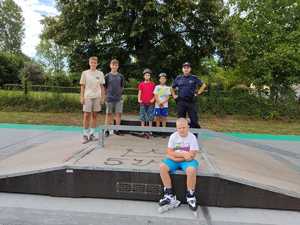 Zdjęcie przedstawia policjanta z młodzieżą w skateparku.