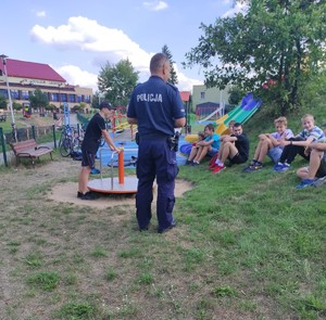 Zdjęcie przedstawia policjanta z młodzieżą podczas pogadanki.