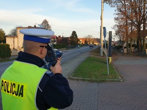 Na zdjęciu policjant prowadzi pomiar prędkości w rejonie cmentarza.