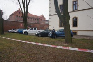 Na zdjęciu widoczna taśma z napisem policja oraz funkcjonariusz prowadzący czynności.