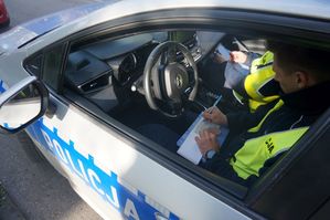 Na zdjęciu policjant wypisujący mandat.