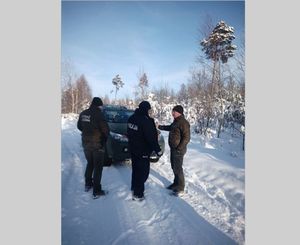 Na zdjęciu samochód , strażnik leśny oraz policjant na tle ośnieżonego lasu.