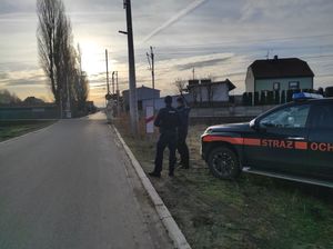 Na zdjęciu widoczni funkcjonariusze policji i Służby Ochrony Kolei, w tle przejazd kolejowy oraz samochód Służby Ochrony Kolei.