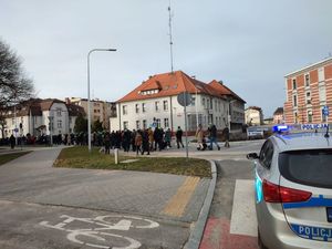 Na zdjęciu widoczny przemarsz orszaku złożonego z wiernych, za nimi jadący radiowóz, w tle budynek lublinieckiej komendy.