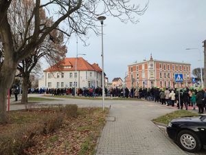 Na zdjęciu widoczny orszak, za nim policyjny radiowóz w tle budynek lublinieckiej komendy.