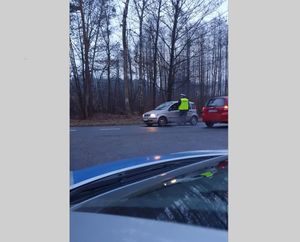 Na zdjęciu widoczny policjant który bada kierujących samochodami na drodze urządzeniem służącym do do badania trzeźwości.