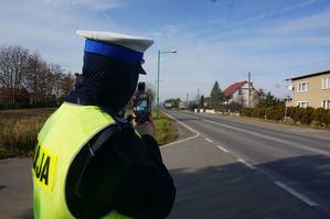 Na zdjęciu widoczny policjant ruchu drogowego mierzący prędkość na drodze.