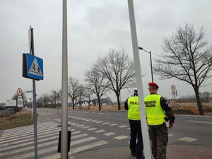 Na zdjęciu widoczny policjant z funkcjonariuszem Żandarmerii Wojskowej sojący przy drodze i mierzący prędkość.