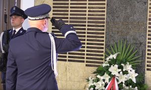 widoczna sylwetka Policjanta oddającego honor w kierunku pomnika upamiętniającego poległych Policjantów