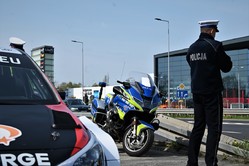 Na zdjęciu widać policyjny motocykl oraz stojącego tyłem policjanta.