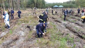 na zdjęciu widoczni policjanci sadzący drzewka