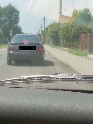 na zdjęciu widoczne jest auto w ciemnym kolorze jadące ulica