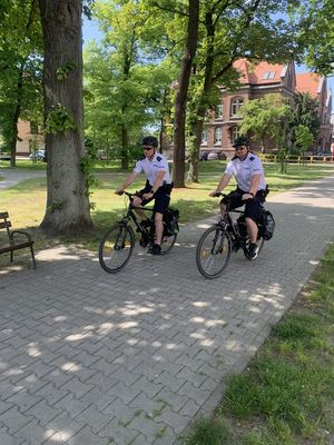 NA ZDJĘCIU WIDOCZNI SA POLICJANCI W MUNDURACH , JADACY NA ROWERACH