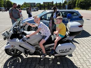 na zdjęciu widoczni są dwaj chłopcy siedzący na motocyklu policyjnym