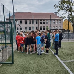 na zdjęciu widoczny jest budynek szkoły w Ciasnej oraz duża grupa dzieci stojąca na boisku szkolnym