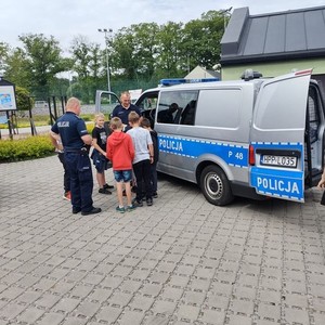 na zdjęciu widoczny jest radiowóz policyjny typu bus oznakowany obok policjanci i dzieci ze szkoły podstawowej w Ciasnej