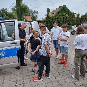 na zdjęciu widoczny jest radiowóz policyjny typu bus oznakowany obok policjanci i dzieci ze szkoły podstawowej w Ciasnej