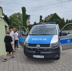 na zdjęciu widoczny jest oznakowany radiowóz typu bus i dzieci