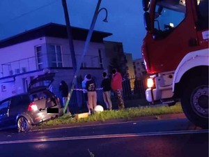 na zdjęciu widoczne jest uszkodzone auto marki Volkswagen stojące przy latarni ulicznej , jak również przód samochodu straży pożarnej