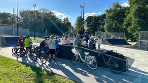 na zdjęciu widoczny jest umundurowany policjant rozmawiający z grupa dzieci  siedzących przed nim widoczne są również ich rowery w tle widoczny jest skatepark w Boronowie