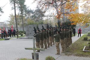 na zdjęciu widoczny jest oddział umundurowanych żołnierzy oddający salwę honorowa