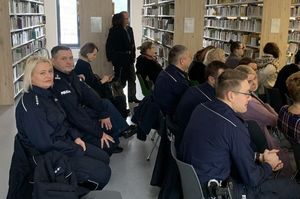 na zdjęciu widoczni są umundurowani policjanci siedzący na krzesłach w bibliotece