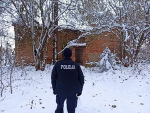 na zdjęciu widoczny jest policjant umundurowany stojący przed pustostanem,