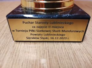 na zdjęciu widoczna jest tabliczka zamieszczona na pucharze, na której napisane jest ze Komenda w Lublińcu zajęła drugie  miejsce w turnieju siatkówki