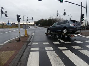 na zdjęciu widoczna jest laweta na której stoi samochód osobowy , stoi na środku skrzyżowania