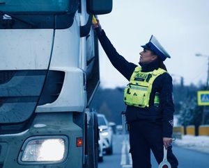 na zdjęciu widoczna jest umundurowana policjantka z urządzeniem do badania trzeźwości stojąca przy samochodzie ciężarowym