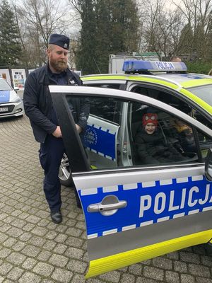 na zdjęciu widoczny jest umundurowany policjant i oznakowany radiowóz