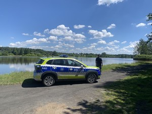 na zdjęciu widoczny jest oznakowany radiowóz  umundurowany policjant