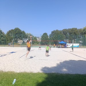 na zdjęciu widoczni są mężczyźni w strojach sportowych grający w piłkę plażową