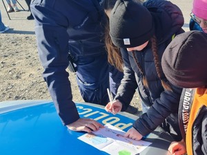 na zdjęciu widoczne są dzieci pochylone nad kartka na której jest narysowany rebus , który maja rozwiązać