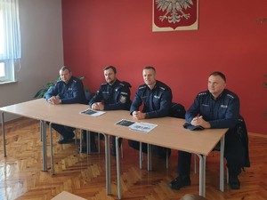 na zdjęciu widocznych  jest czterech umundurowanych policjantów siedzących za stołem