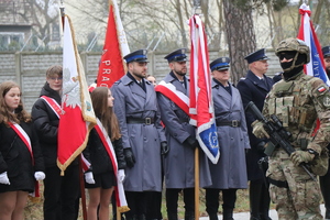 na zdjęciu widocznych  jest trzech policjantów w mundurach galowych policjant w środku trzyma sztandar jednostki Policji w Lublińcu