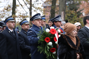 na zdjęciu widoczni są policjanci w galowych mundurach jeden z nich trzyma wieniec