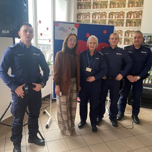 na zdjęciu widocznych jest czterech policjantów oraz dyrektor szkoły za ich plecami widoczne jest duże czerwone serce