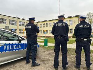 na zdjęciu widocznych jest trzech umundurowanych policjantów stojących obok oznakowanego radiowozu