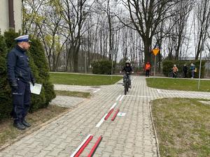 na zdjęciu widoczne jest dziecko jadące na rowerze i stojący umundurowany policjant