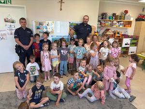 NA ZDJĘCIU WIDOCZNI SA DWAJ POLICJANCI ORAZ GRUP DZIECI PRZEDSZKONYCH