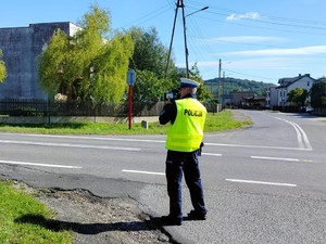 na zdjęciu widoczny jest umundurowany policjant z urządzeniem do pomiaru prędkości