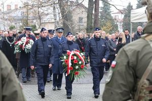 widoczna delegacja Komendy Powiatowej Policji w Lublińcu niosąca kwiaty