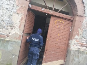 na zdjęciu widoczny jest umundurowany policjant stojący przy pustostanie