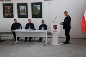 na zdjęciu widocznych  jest troje umundurowanych policjantów siedzących za stołem przy mównicy stoi umundurowany funkcjonariusz służby ochrony kolei