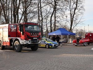 na zdjęciu widoczny jest duży wóz strażacki obok stoi radiowóz namiot policyjny obok drugi wóz straży pożarnej i łódka