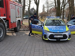 na zdjęciu widoczny jest radiowóz policyjny oraz umundurowany policjant