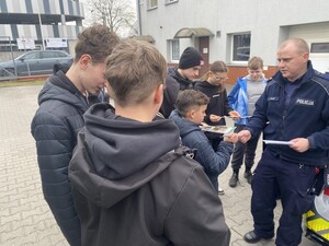 policjant rozdaje odblaski wokół niego stoi młodzież